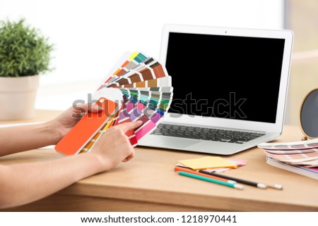Designer with paint color palette samples at table, closeup