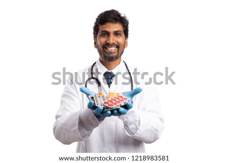 Trustworthy indian male doctor holding medicine blisters in palm with smile as recommending concept isolated on white