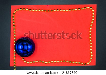 Wallpaper background of red copy space with golden border chord and blue christmas glittered ball on black.