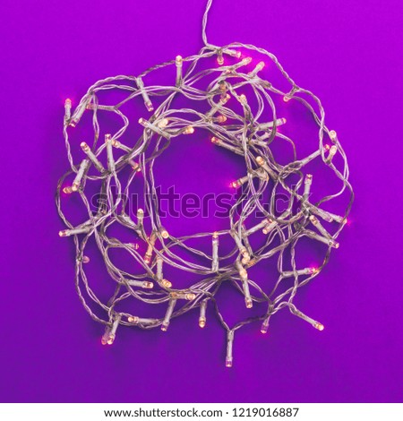 Creative Christmas lights decoration frame with purple background. Minimal flat lay concept. 