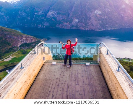 Aerial view. Tourist woman with camera enjoying fjord view Aurlandsfjord landscape from Stegastein viewing point. Norway Scandinavia. National tourist route Aurlandsfjellet.