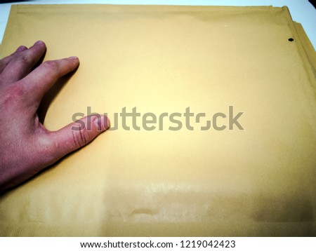 Close-up Of Mailman Delivering Mail To Person Over White Background.  Brown envelope back on wooden table. Man hand. Letter top view. Objects with clipping path. Copy space for text and design.