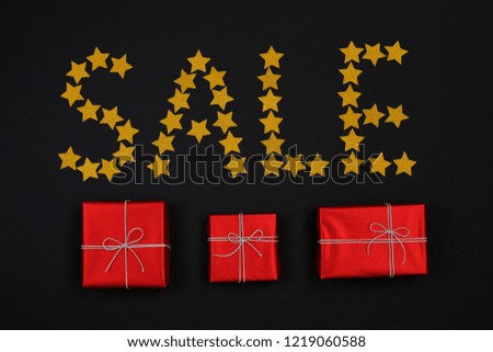 Word sale made from gold star and red gift boxes with presents on black background. Flat lay. Gift box with BLACK FRIDAY SALE. shopping concept.