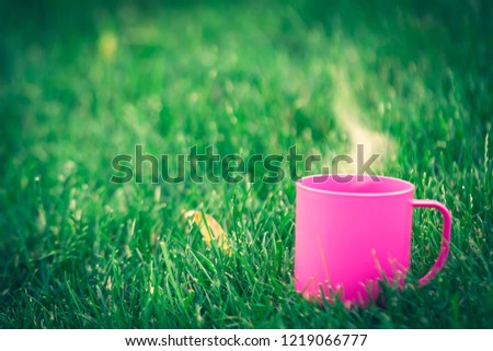 pink Cup of coffee with steam on green lawn