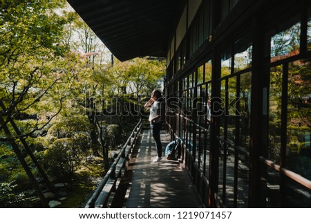 
Happy middle-aged woman touring the different temples of Kyoto in Japan at the beginning of autumn. Taking many pictures. Travel photography. Lifestyle.