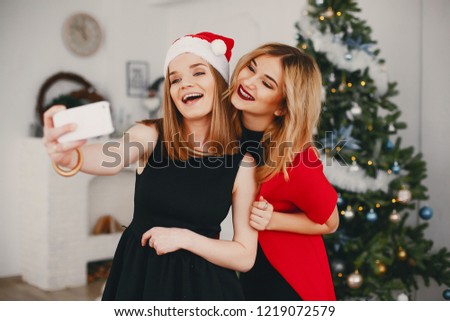 In a beautiful decorated room with a Christmas tree is standing a two young girs 