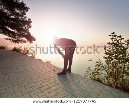 Middle aged runner stop for breath. Sportsman takes a break and looking to morning Sun above horizon Royalty-Free Stock Photo #1219077745