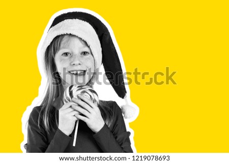 Little red haired and freckled face girl dressed in Santa's hat holds sweet lollipop and dreams about gifts. Christmas and New Year advertising concept. Magazine style fashion collage