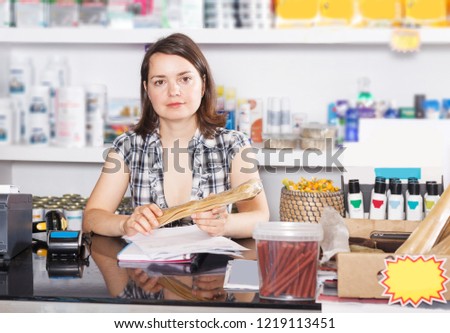 portrait of young woman seller working  with documents and goods in pet store