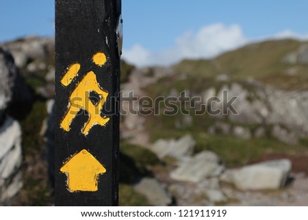Yellow trekking sign on a wooden pole