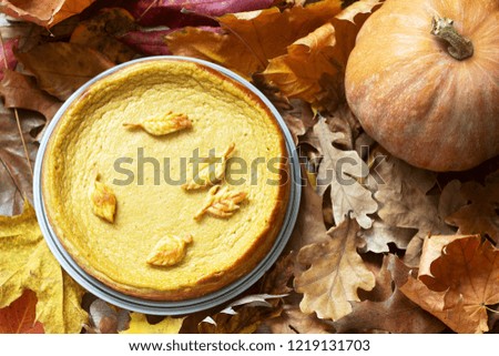 Traditional American pumpkin homemade cake, decorated with cookies on a background of pumpkins and autumn leaves.