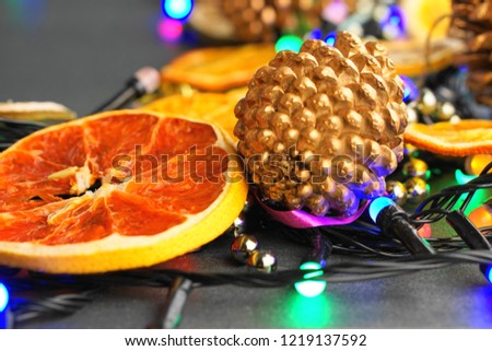 dark surface decorated with gerlanda, golden spruce cones, dried oranges with a place for text in the center