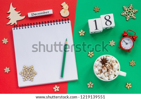 Winter composition. Wooden calendar December 18th Cup of cocoa with marshmallow, empty open notepad with pencil, snowflake, alarm clock on red and green background. Top view Flat lay Mockup