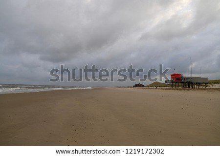 empty beach on a cloudy day  in the quiet coastal small town, the Netherlands. lifesaving station on a background.