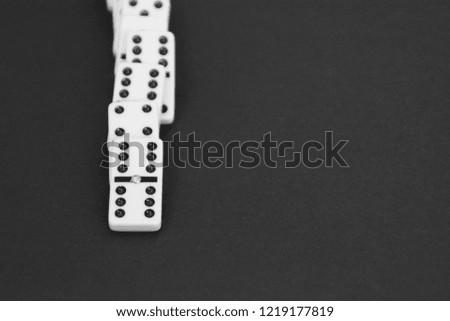 White dominoes lie in a row against a dark background as a symbol of an ongoing process and the past opportunities of this activity