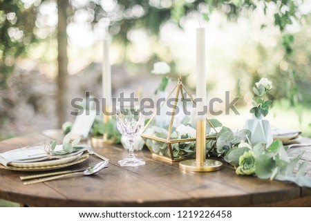Gold and pastel wedding dinning table decoration. Geometic shapes, rustic decor, eucalyptus branches, candles, menu. Bokeh background.
