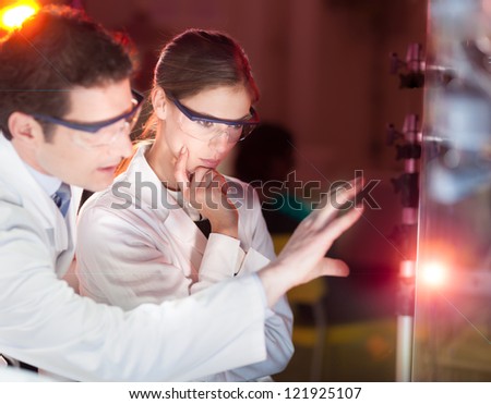 Portrait of a focused electrical engineering researchers in their working environment checking the phenomenon of breaking laser beam on the glass surface. Royalty-Free Stock Photo #121925107