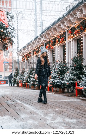 Beautiful russian girl in a cloud day in winter style clothes, walking in Tverskaya Square in Christmas time
