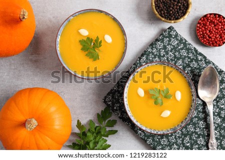 Pumpkin soup in bowls on grey background. Top view.