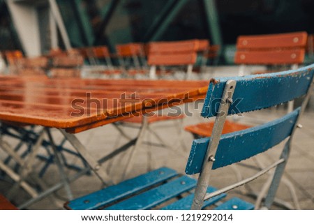 The end of season in beer garden with rain drop on wooden chair during late autumn morning