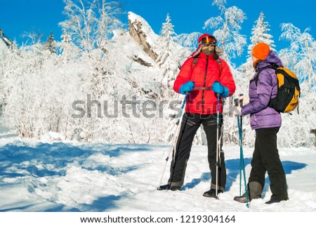 man and woman hikers with backpacks and nordic walking poles in a frosty winter landscape