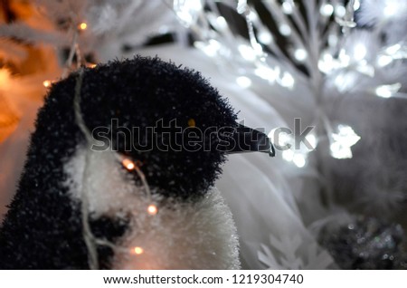 Penguin toy. Christmas decoration and luminous garland, and many glowing light bulbs.