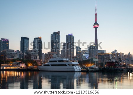 A view of Toronto downtown over the marina  with street lights, buldings and yahts at sunset