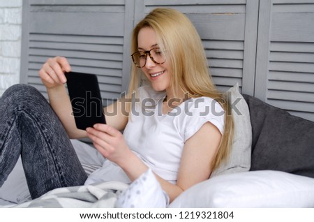 Young attractive woman with long blonde hair reading book in the bed, selective focus