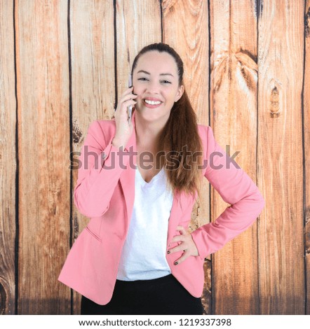 Confident young business woman holding a mobile phone against a wooden background