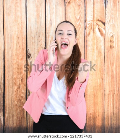 Confident business woman holding a mobile phone against a wooden background