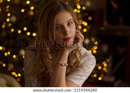Woman sitting in front of a christmas tree in a white blouse