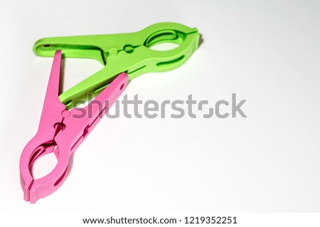 Pink and green cloth peg clamp on a white background