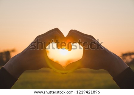 Hands making heart shape with sunset. Close up of woman hands making heart shape gesture.