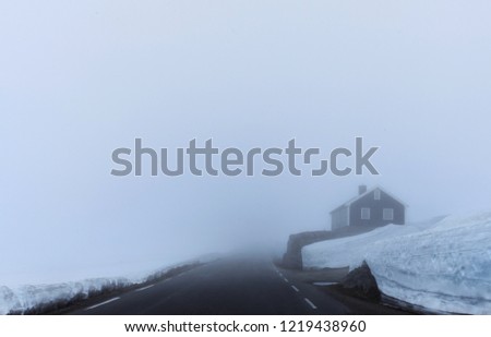 Frozen lonely house in the middle of nowhere in the winter. Heavy fog and a lot of snow.  Royalty-Free Stock Photo #1219438960