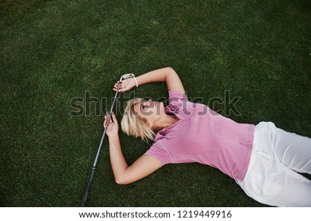 The girl lies on the golf course and relaxes after the game.