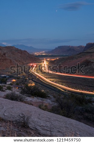 Night time picture of Moab from the entrance of Arches national park in Utah USA. Headlights are flooding the way into the city. 