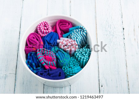 rolled socks in enamel bowl, on white wood table