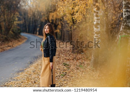 cozy stylish young girl walk at autumn colorful park alone