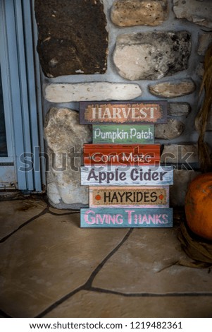 Wooden signs indicating fall festivities and goodies placed outside an entryway.