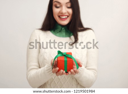 Young excited woman holding gift, trying to guess what inside over white background. Surprise present for celebration, Birthday party concept, copy space