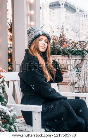 Beautiful russian girl in a cloud day in winter clothes with christmas ball in hands having fun in Tverskaya Square in Christmas time