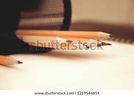 album and pencils in pencil stand on wooden background selective focus close-up