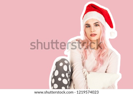 Attractive smiling young girl dressed in Santa's hat hugs the pillow and dreams about gifts. Christmas and New Year advertising concept. Magazine style fashion collage