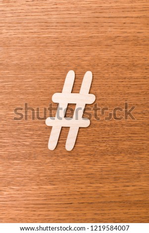 Hashtag sign made of wooden material on wooden background. Top view
