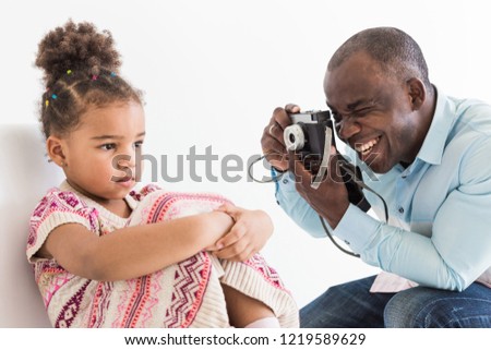 Young father with his cute little daughter taking pictures of each other on an old vintage camera