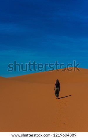Girl walk in Erg Chebbi Desert, Sahara Desert near Merzouga, Morocco