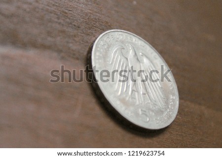 5 Deutsche mark from 1981 laying on a vintage wooden table, side view, close up
