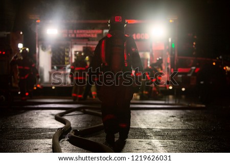 Firefighter walking on a burning building emergency Royalty-Free Stock Photo #1219626031