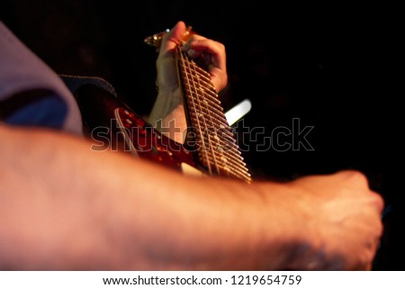 Electric guitar player, closeup photo with soft selective focus on dark