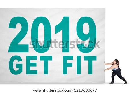 Picture of obese woman wearing sportswear while pushing a text of 2019 get fit on the board